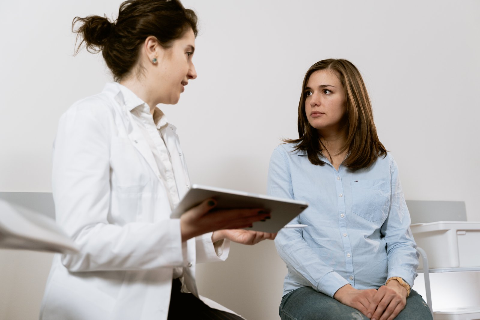 Ženska sedi pri ginekologu in se pogovarja z njim